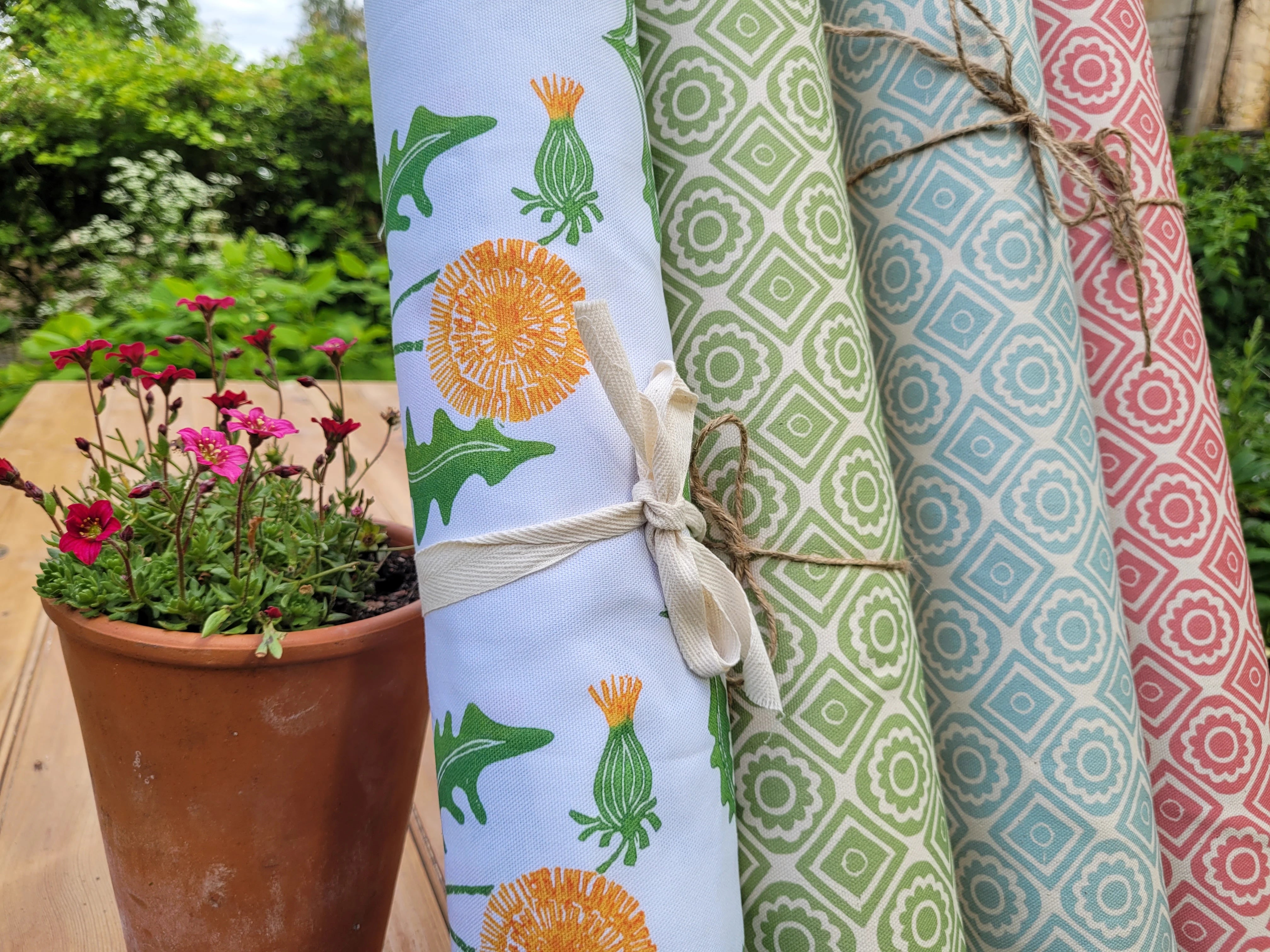 four rolls of lino block printed fabric in dandelion and rebecca designs by lizzie mabley