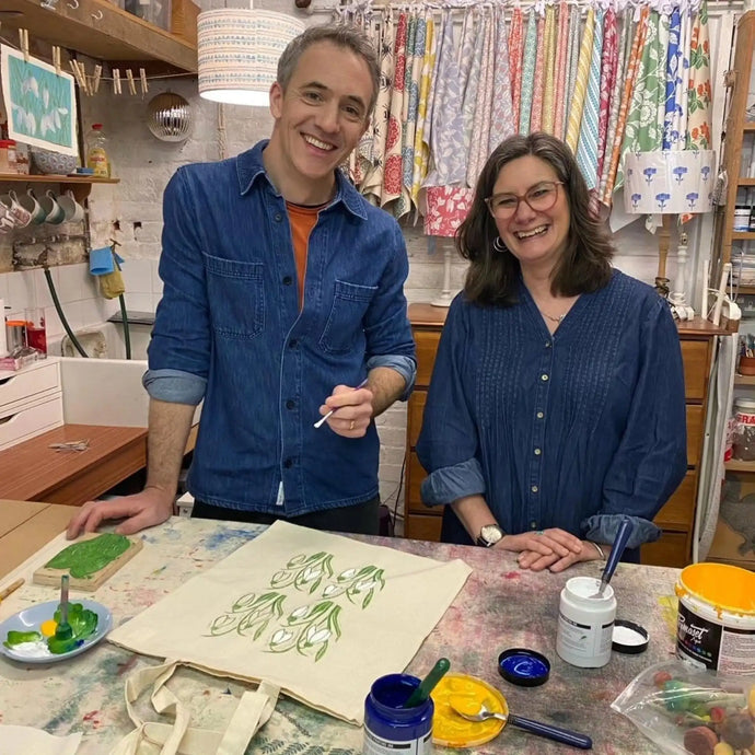 Lizzie Mabley and Joe Crowley in a workshop setting with art supplies and fabric.