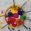 Artistic palette with colorful paint and brushes on a paint-splattered background