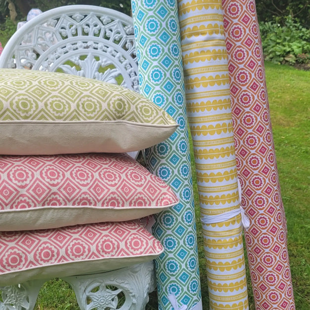 cushions and rolls of  fabric designed and lino cut by lizzie mabley set on a garden chair