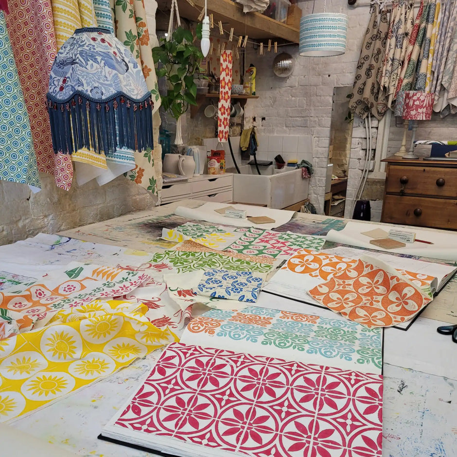Colorful fabric samples on a table with an artists workshop in the background